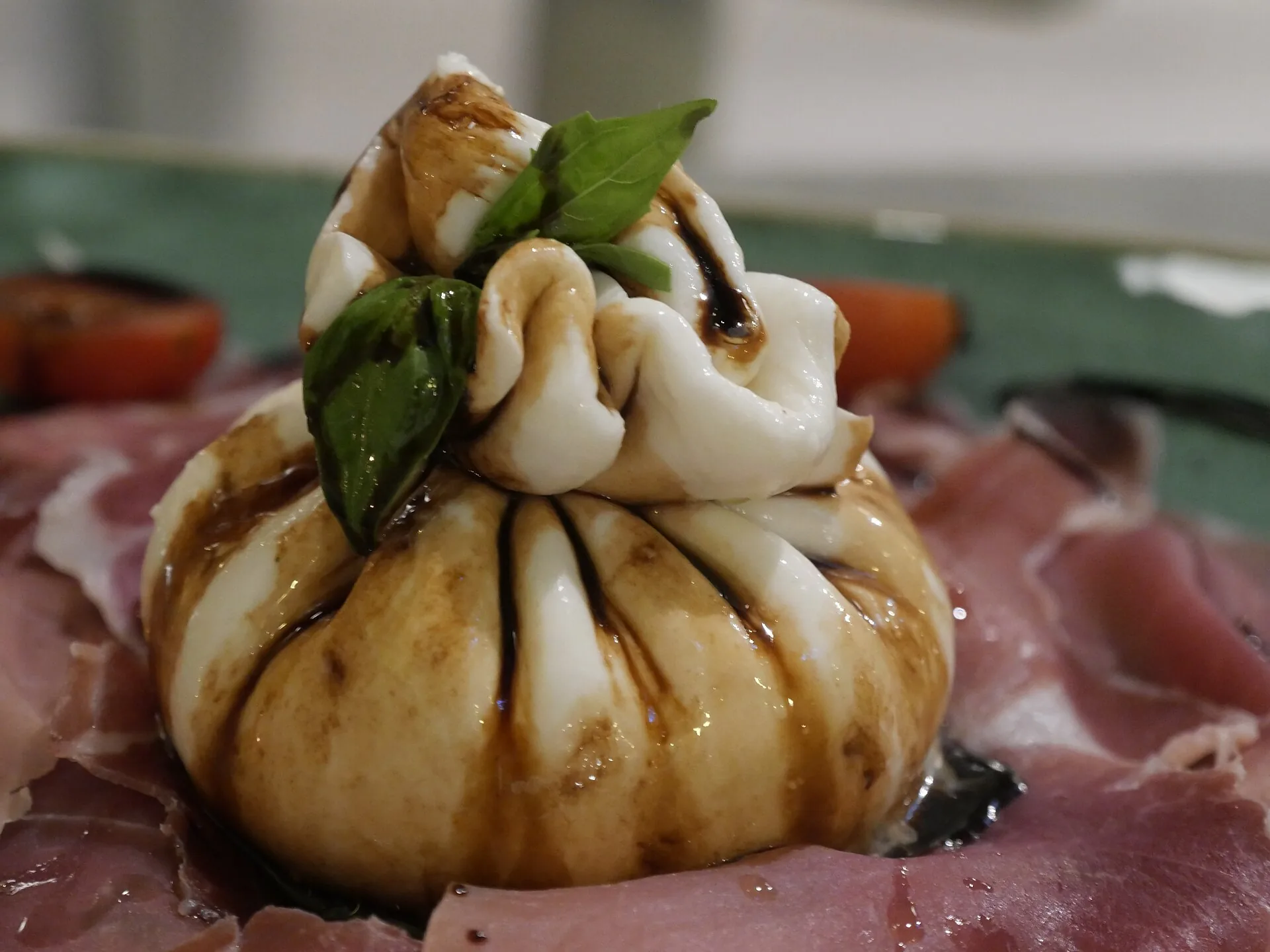 Una mozzarella di bufala annodata servita su un piatto di affettati